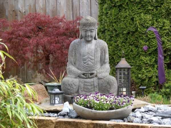 Zu sehen ist eine große Buddha Statue in einem Garten